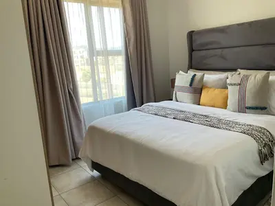 a bedroom with a large bed with pillows and a window at Cozy nest apartment in Pretoria