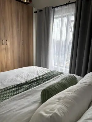 a bedroom with a bed with green pillows and a window at Cozy nest apartment in Pretoria
