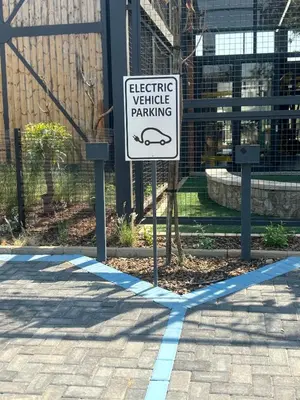 a sign that says electric vehicle parking on a sidewalk at Cozy nest apartment in Pretoria