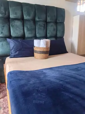 a bed with a blue headboard with a basket on it at Sunset Hideaway in Pretoria