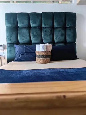 a bed with a blue padded headboard with a basket on it at Sunset Hideaway in Pretoria
