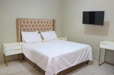 a bedroom with a white bed and a flat screen tv at Okuhlekwethu Guesthouse in Witbank