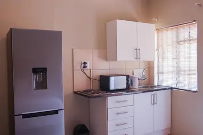 a kitchen with a stainless steel refrigerator and white cabinets at Okuhlekwethu Guesthouse in Witbank