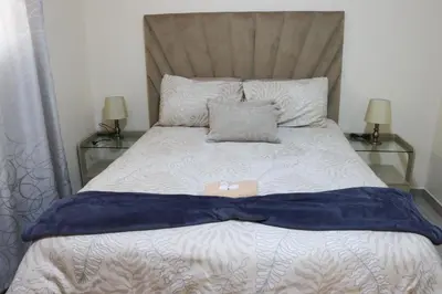a bed with a blue blanket and two glass tables at Okuhlekwethu Guesthouse in Witbank