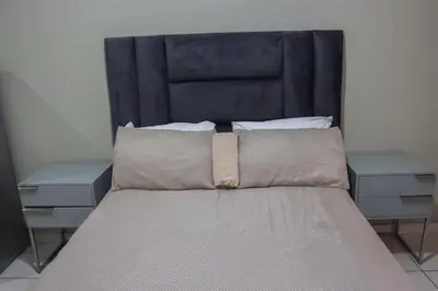 a bed with a black headboard and two night stands at Okuhlekwethu Guesthouse in Witbank