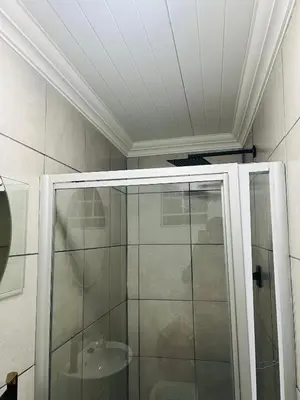 a shower with a glass door in a bathroom at Sunset Hideaway in Pretoria