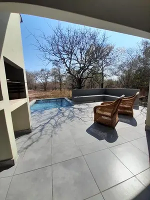 a patio with two chairs and a swimming pool at Chikunda Hayes in Marloth Park