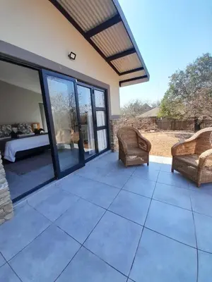 a patio with a bed and two chairs on it at Chikunda Hayes in Marloth Park