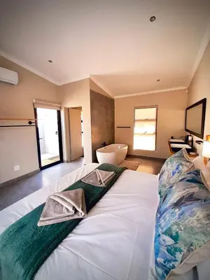 a large white bed in a room with a bathroom at Krugers elegant escape The Kop in Marloth Park