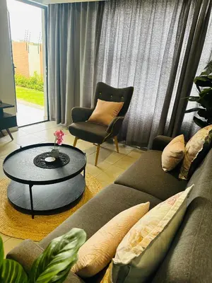 a living room with a couch and a table and a chair at Serenity stay in Kempton Park
