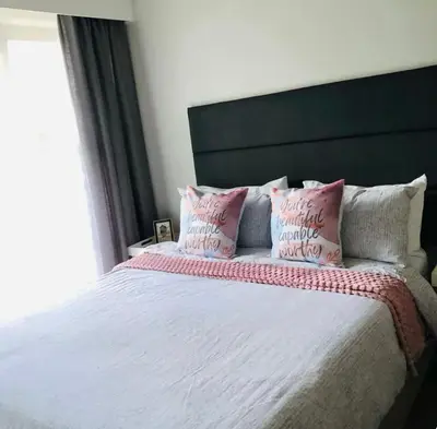 a bedroom with a large bed with pink pillows at Serenity stay in Kempton Park