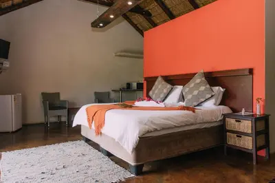 a bedroom with a large bed with an orange wall at Kruger View Chalets in Malelane
