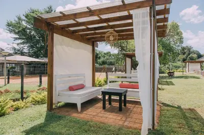 a wooden pergola with a bench and a table at Kruger View Chalets in Malelane