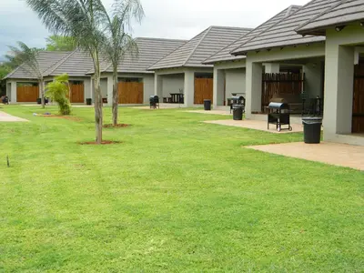 a house with a yard with a palm tree in it at Kruger View Chalets in Malelane