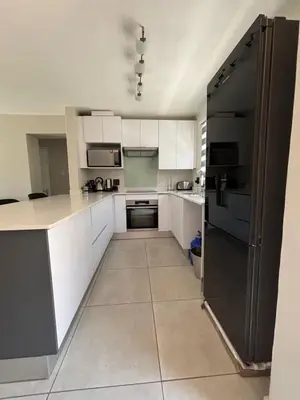 a kitchen with white cabinets and a black refrigerator at 2 Bedrooms Apartment - Hartbeespoort Dam in Hartbeespoort
