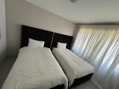 two beds sitting next to a window in a bedroom at 2 Bedrooms Apartment - Hartbeespoort Dam in Hartbeespoort