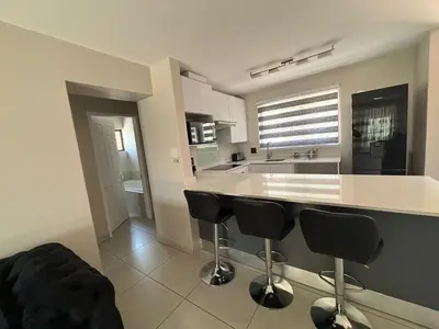 a kitchen with a counter and two bar stools at 2 Bedrooms Apartment - Hartbeespoort Dam in Hartbeespoort