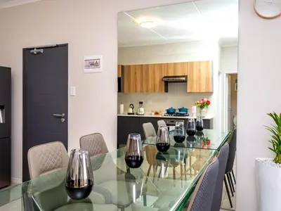 a dining room with a glass table with wine glasses at Glen Haven in Midrand