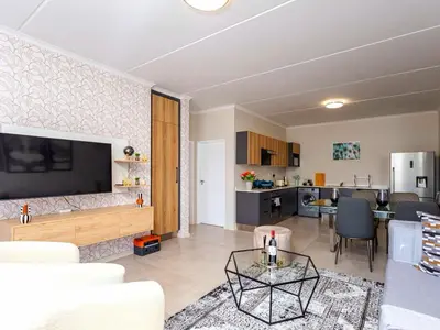 a living room with a couch and a tv and a kitchen at Glen Haven in Midrand