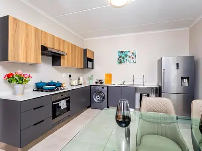 a kitchen with stainless steel appliances and a glass table at Glen Haven in Midrand