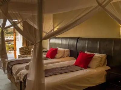 a bedroom with a canopy bed with red pillows at Mjejane River Lodge in Hectorspruit