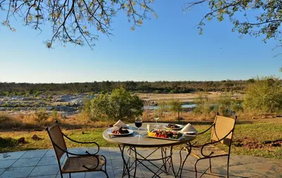 a table with a bowl of food and two chairs at Mjejane River Lodge in Hectorspruit