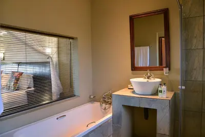 a bathroom with a sink and a tub and a mirror at Mjejane River Lodge in Hectorspruit