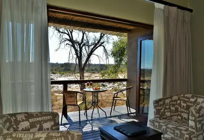 a living room with a balcony with a table and chairs at Mjejane River Lodge in Hectorspruit