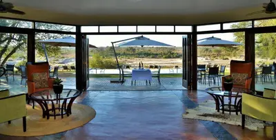 a patio with tables and chairs and umbrellas at Mjejane River Lodge in Hectorspruit
