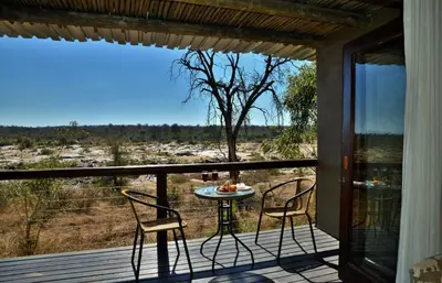 a patio with two chairs and a table on a deck at Mjejane River Lodge in Hectorspruit