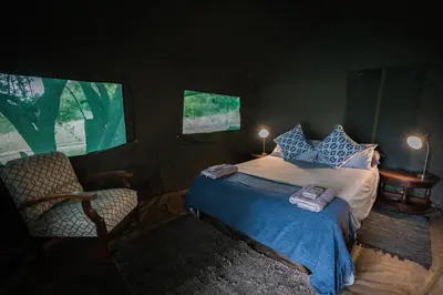 a bedroom with a bed and a chair in a tent at Maninghi Lodge in Balule Game Reserve