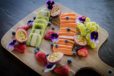 a plate of fruit and vegetables on a cutting board at Maninghi Lodge in Balule Game Reserve