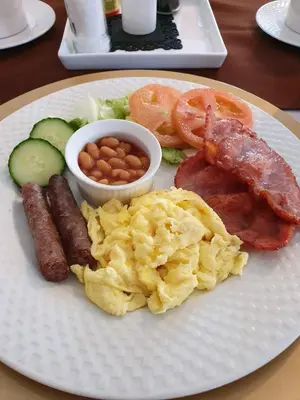 a plate of breakfast food with sausage eggs potatoes and beans at Harmony Guesthouse in Nelspruit