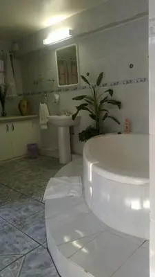 a white bathroom with a tub and a sink at Harmony Guesthouse in Nelspruit