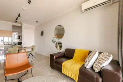 a living room with a brown couch and a kitchen at Jabba at Ellipse Waterfall in Midrand