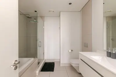 a white bathroom with a shower and a toilet at Jabba at Ellipse Waterfall in Midrand