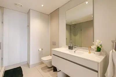 a white bathroom with a sink and a toilet at Jabba at Ellipse Waterfall in Midrand