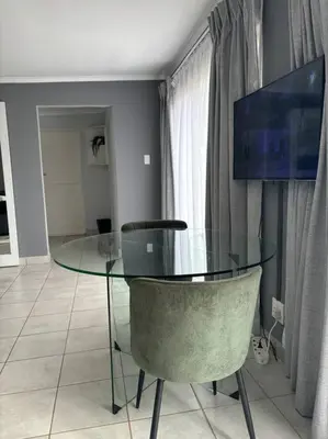 a glass table and a chair in a room at Serene Oasis in Tierpoort