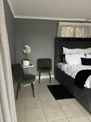 a bedroom with a bed and a chair and a table at Serene Oasis in Tierpoort