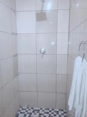 a bathroom with a shower with a black and white tile floor at Choosers Express Hotel Room 6 in Rooihuiskraal
