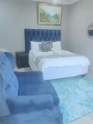 a bedroom with a blue bed and a blue couch at Choosers Express Hotel Room 6 in Rooihuiskraal