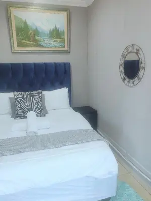 a bed with a blue headboard in a room at Choosers Express Hotel Room 6 in Rooihuiskraal