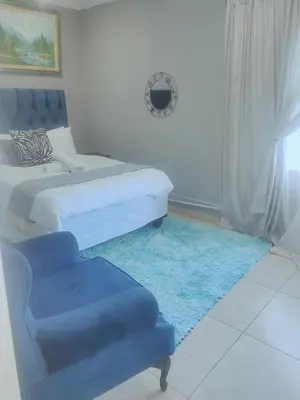 a bedroom with a bed and a blue chair at Choosers Express Hotel Room 6 in Rooihuiskraal
