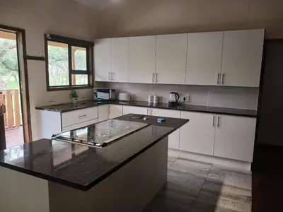 a kitchen with white cabinets and a black counter top at Hippo Waterfront Lodge in Nelspruit