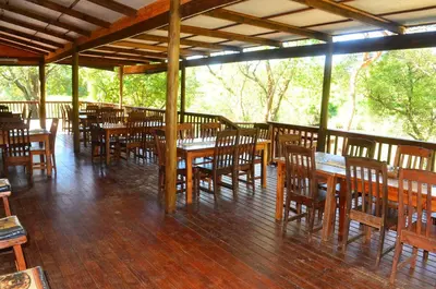 an empty restaurant with wooden tables and chairs at Hippo Waterfront Lodge in Nelspruit