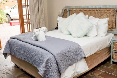 a bed with a teddy bear sitting on top of it at 61 On Ireland Guest House and Conferencing in Polokwane