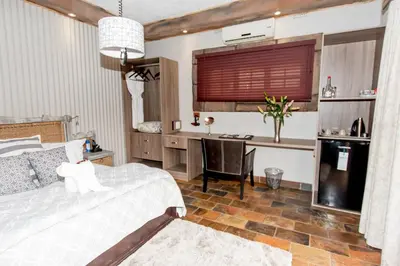 a bedroom with a bed and a desk with a computer at 61 On Ireland Guest House and Conferencing in Polokwane