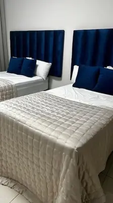 two beds in a room with blue curtains at Micasa apartments in Midrand