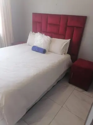 a large bed with a red headboard and white pillows at mokede Iin in Pretoria