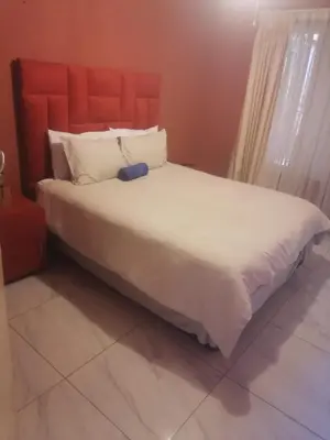 a bedroom with a large white bed with a red headboard at mokede Iin in Pretoria